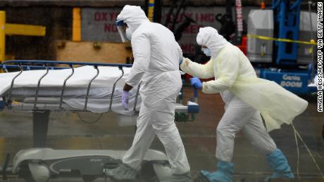 TOPSHOT - Medical personnel move a deceased patient to a refrigerated truck serving as make shift morgues at Brooklyn Hospital Center on April 09, 2020 in New York City. - America&#39;s coronavirus epicenter of New York recorded a new single-day high of 799 COVID-19 deaths Thursday but Governor Andrew Cuomo said the rate of hospitalizations continued to fall. (Photo by Angela Weiss / AFP) (Photo by ANGELA WEISS/AFP via Getty Images)