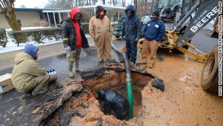 City workers repair a busted water main in McComb, Miss., on Thursday, Feb. 18, 2021.  Winter storms that dumped additional snow and ice on the Deep South plunged thousands of homes and businesses into darkness and left roads impassable across a wide area.  (Matt Williamson/The Enterprise-Journal via AP)