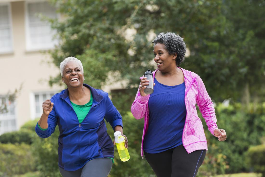 [two older women having a laugh while exercising outdoors]