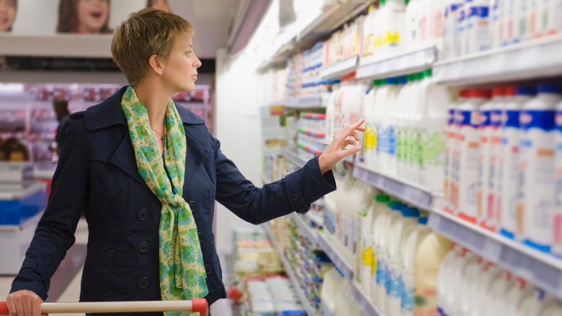 a woman looking at milk in at supermarket and wondering which contain saturated or unsaturated fats 