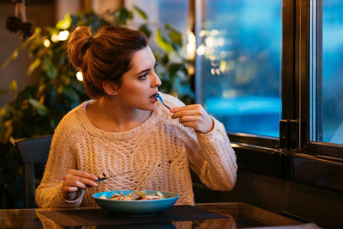 Woman eating food in restaurant looking out of window