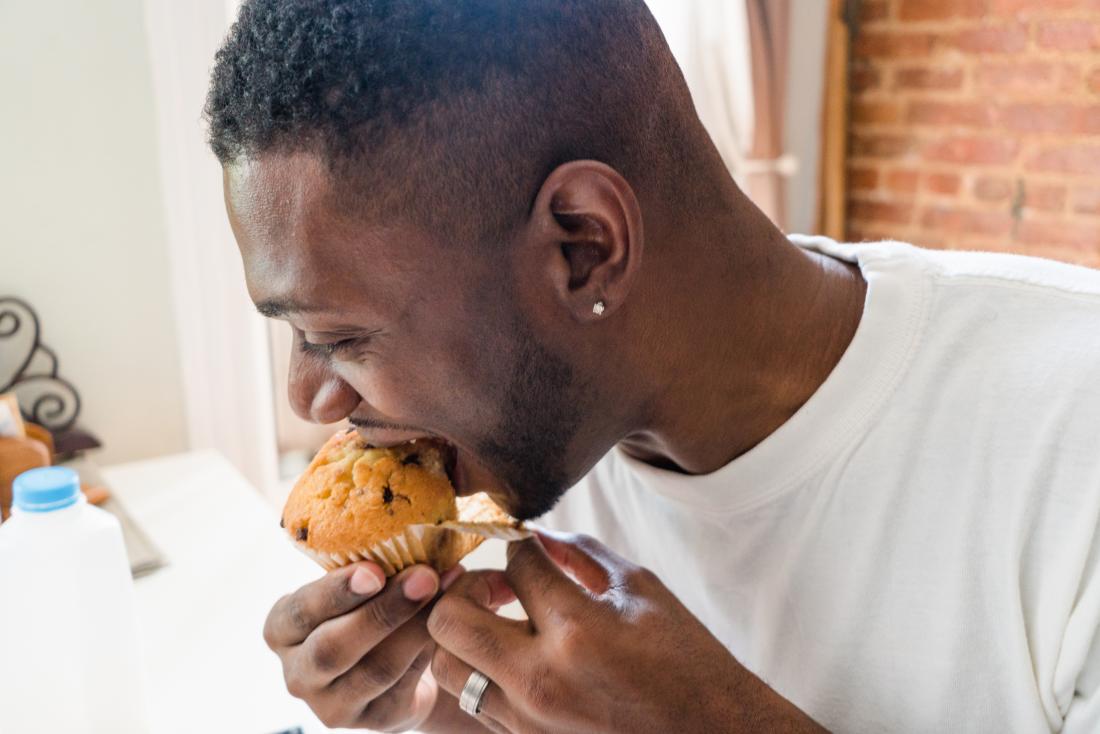 man eating chocolate chip muffin