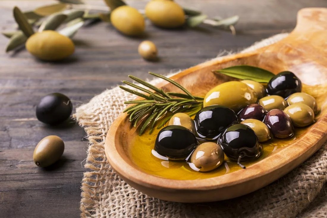 different-types-of-olives-in-oil-in-wooden-bowl