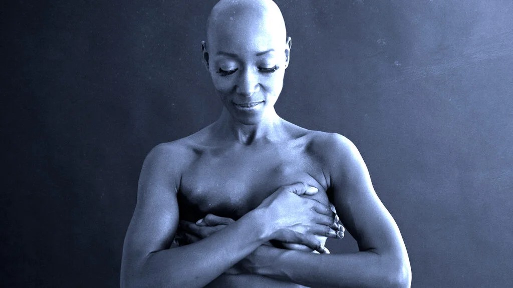 A female with breast cancer holding their breasts.