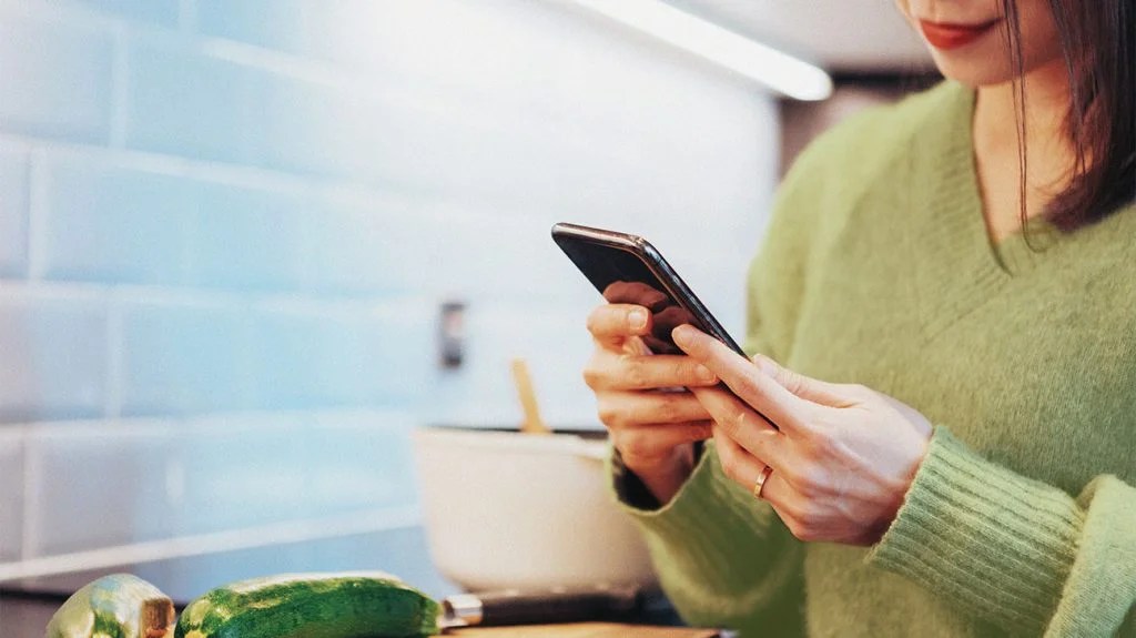 A woman experiencing a weight loss plateau checks the health app on her phone