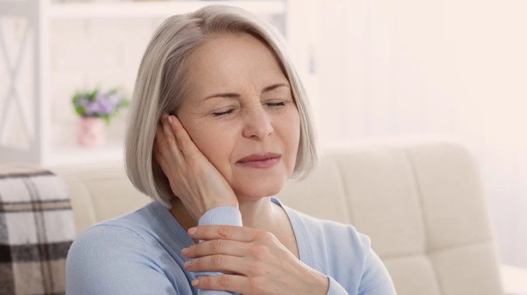 a woman holding her ear because she has a pain there from Meniere's disease