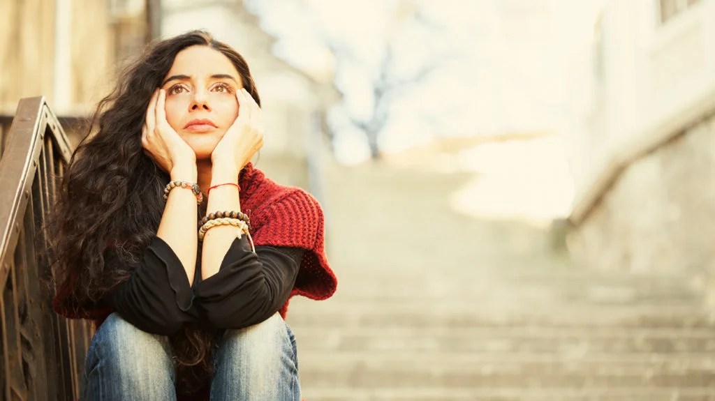 woman sat on the steps worrying about stress effects on the body