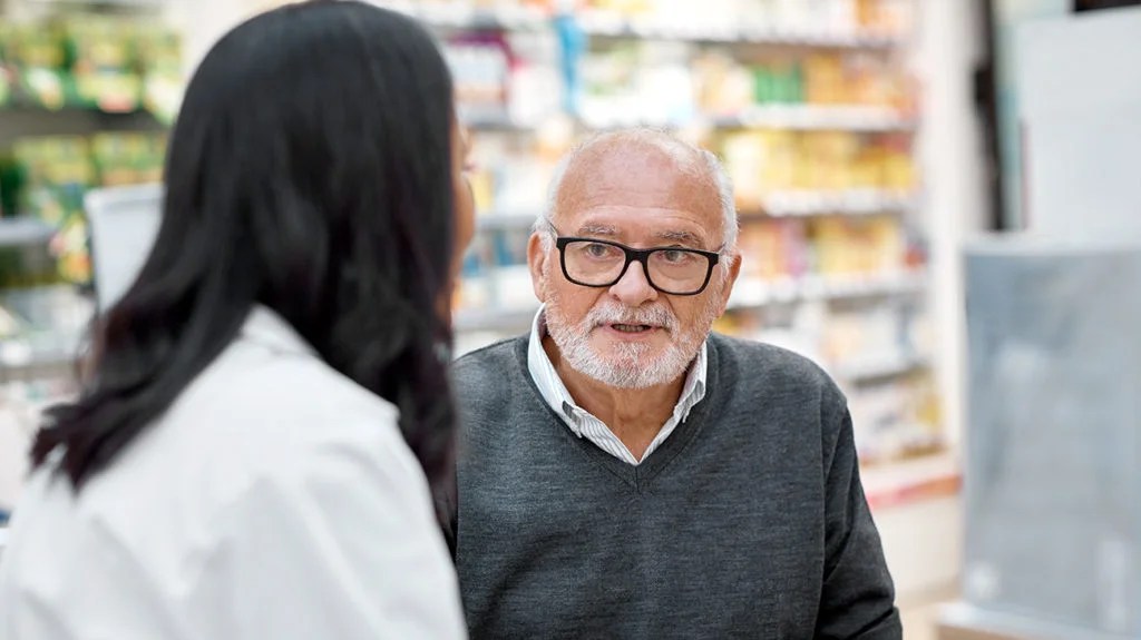 a man talking to a pharmacist about medicare part d costs