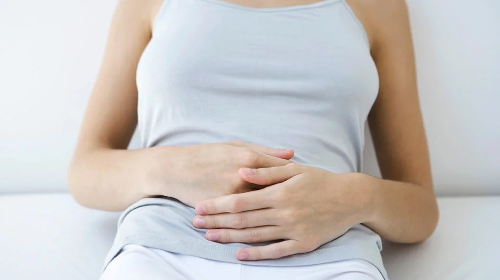 a woman holding her stomach because she has constant nausea