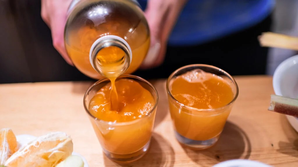 person pouring a glass of kombucha