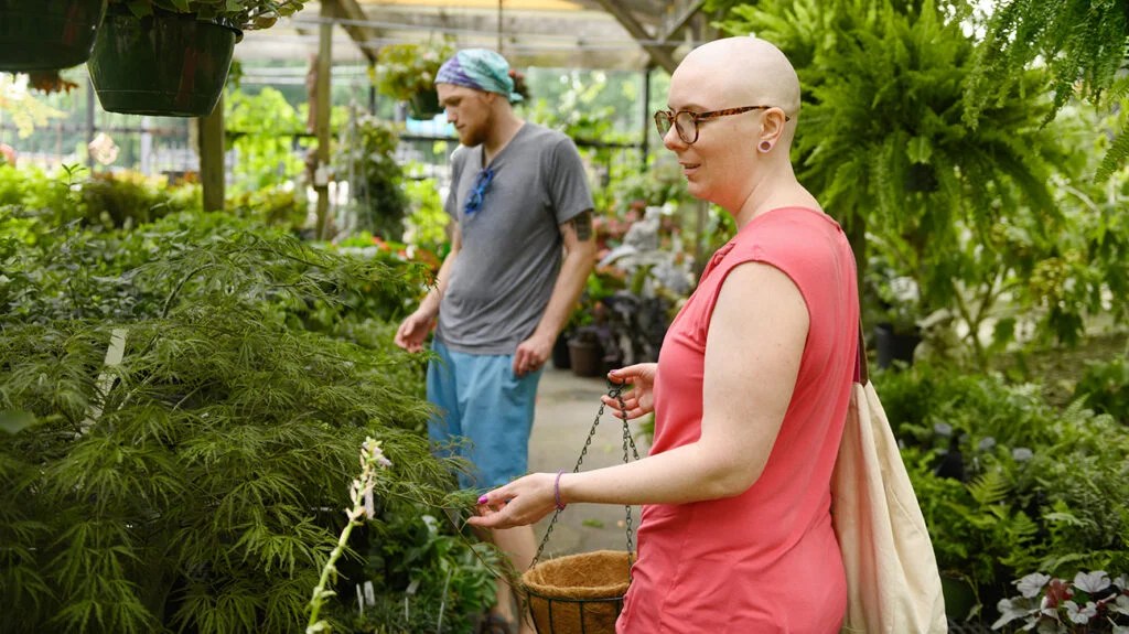 A person, who may have symptoms of advanced breast cancer, looking at flowers.