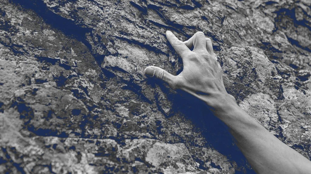 a rock climber's hand gripping a rock face