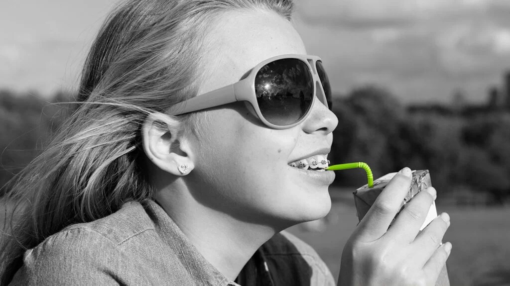 there is a black and white photo of a person wearing sunglasses drinking a carton of fruit juice