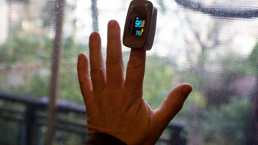 Person using finger blood glucose monitor outdoors