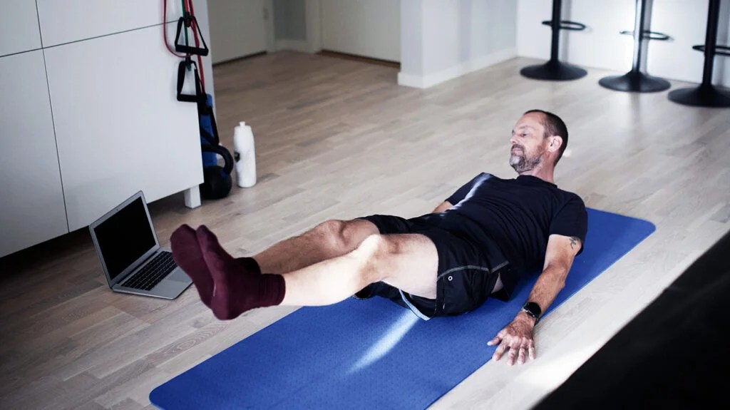 A man on a yoga mat doing sciatica exercises at home.