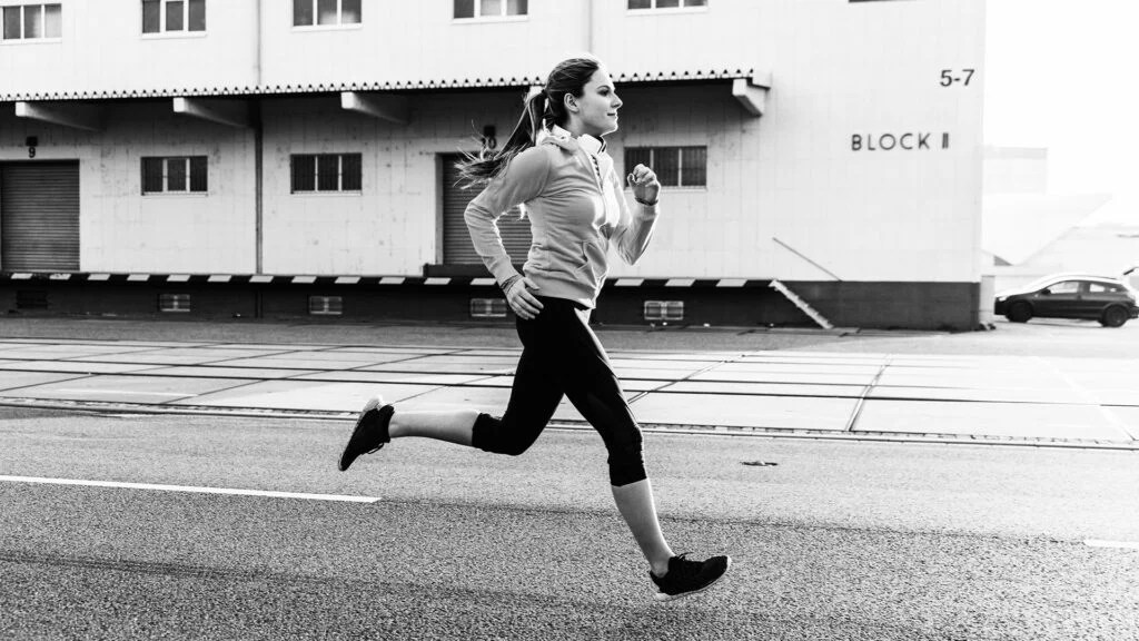 A woman wearing fitness clothing runs in a neighbourhood