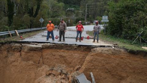 Four workers inspect a washed-away rural road