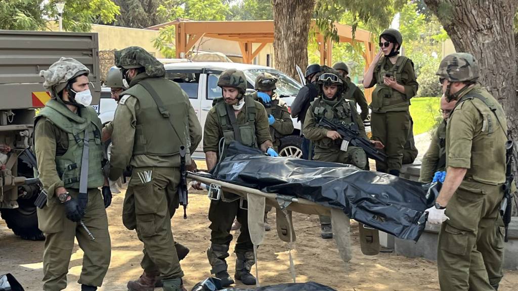 Israeli soldiers move bodies in Kfar Aza kibbutz