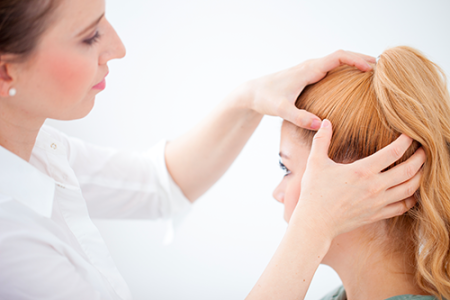 Physician checking woman's scalp