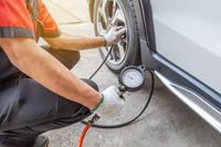 Mechanic Checks Tire Pressure on Car and Inflates Tire