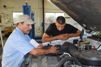 Two men repairing an engine in a garage.