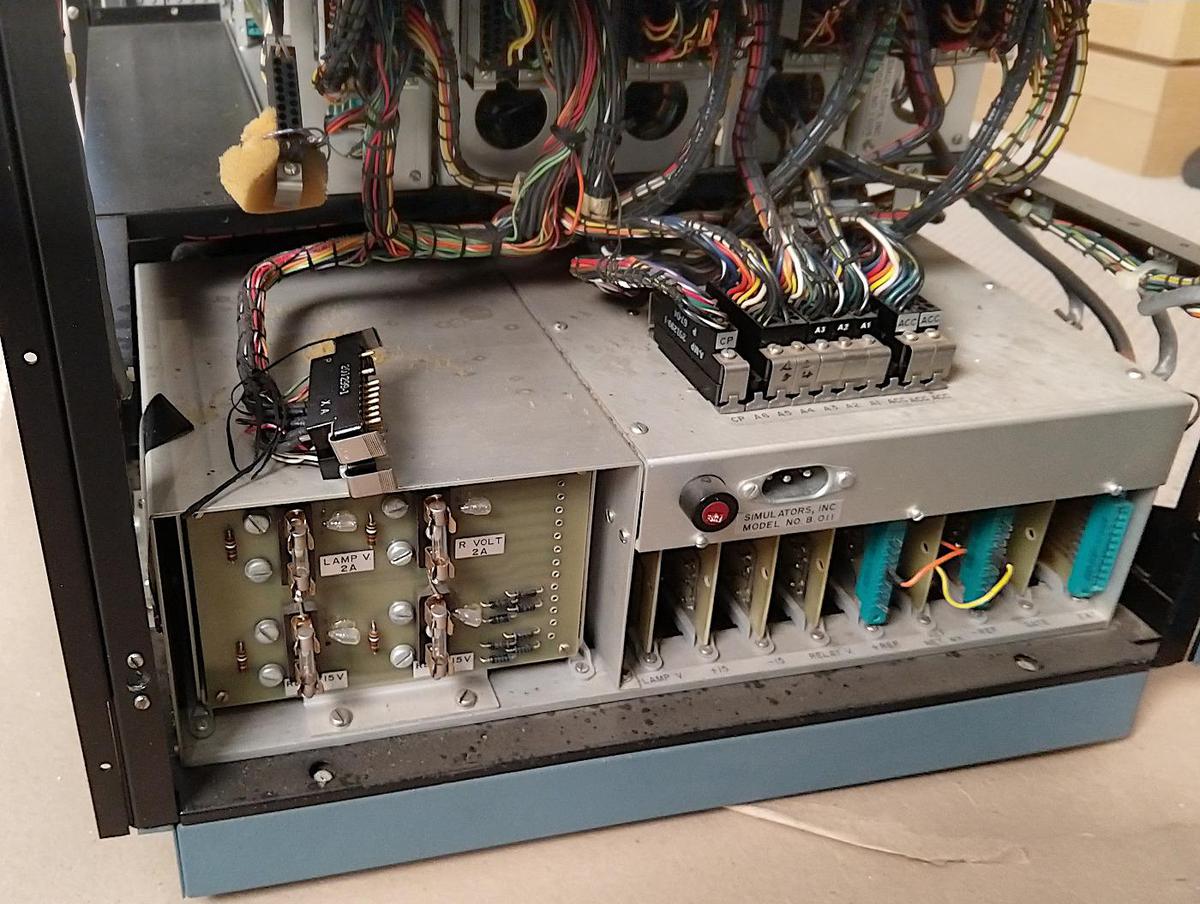 The power supply in the bottom section of the analog computer. The transformer/rectifier section is on the left and the regulator card cage is on the right. Wiring harnesses on top of the power supply connect it to the rest of the computer.