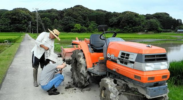 トラクターの車輪についた土を分けてもらった=2024年6月22日、宮崎市上北方、神崎卓征撮影