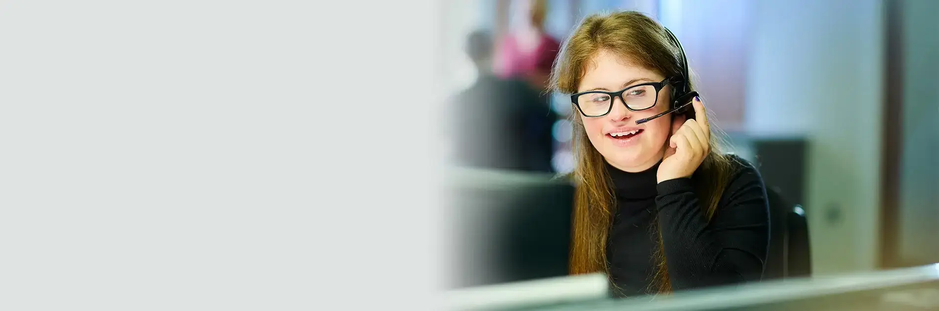 An employee wearing a headset and smiling.