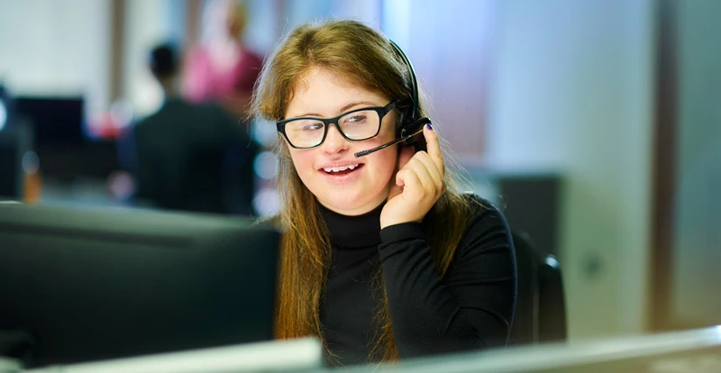 An employee wearing a headset and smiling. (Mobile)