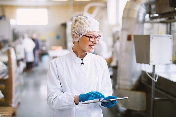 a person in a white lab coat and blue gloves holding a tablet