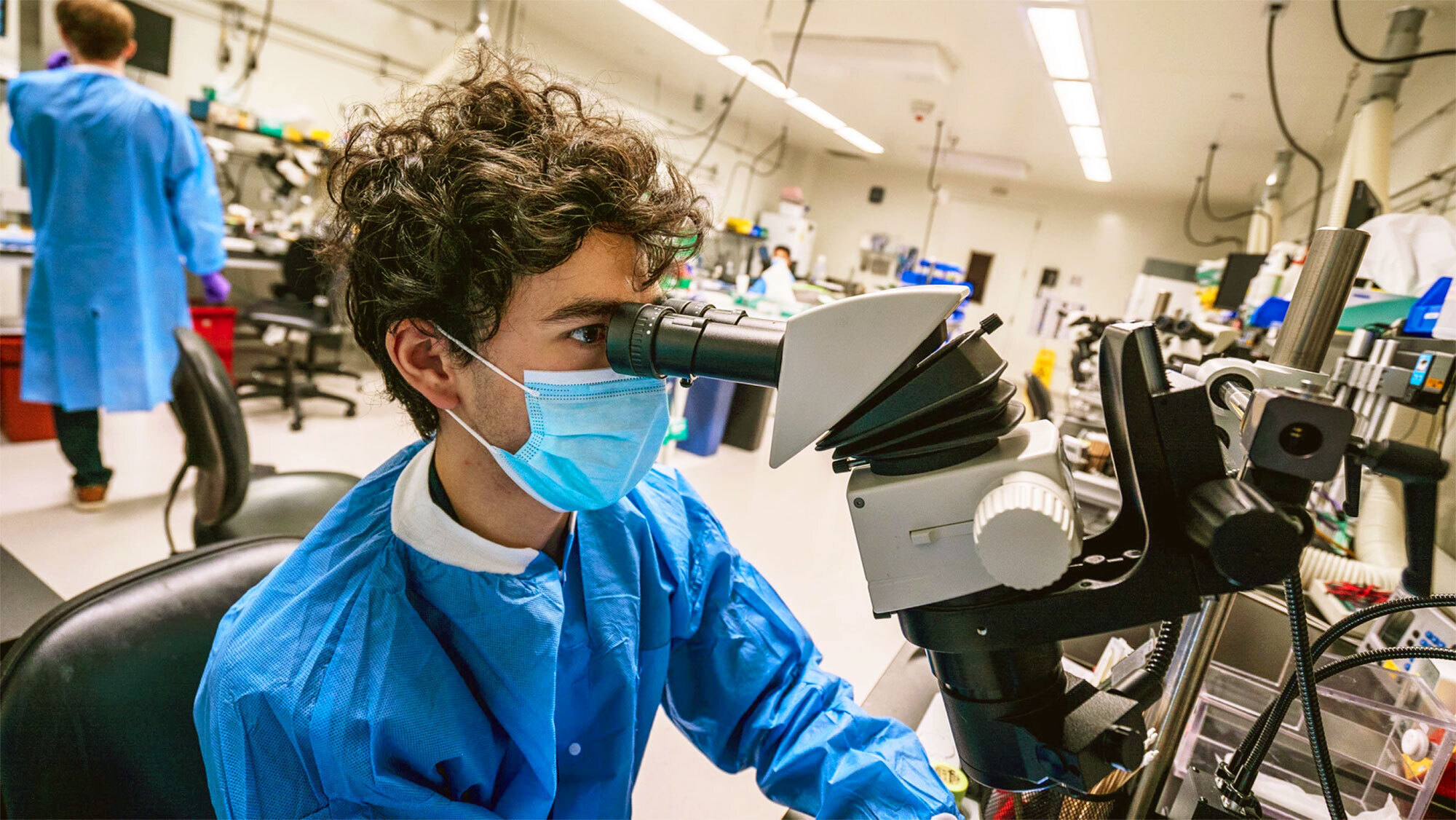 A photo of a researcher from the Allen Institute for Brain Science looking into a microscope.