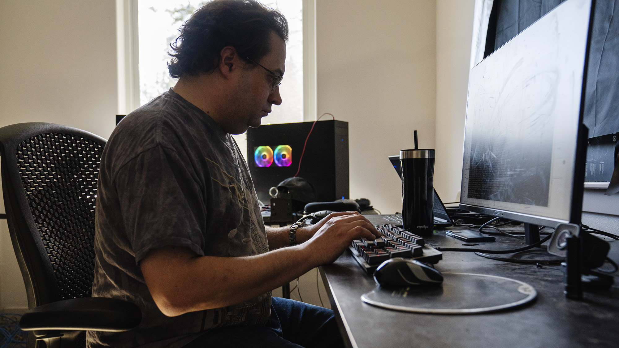 A photo of Tom Scholl, AWS VP and Distinguished Engineer, sitting at his desk at home, working on his computer.