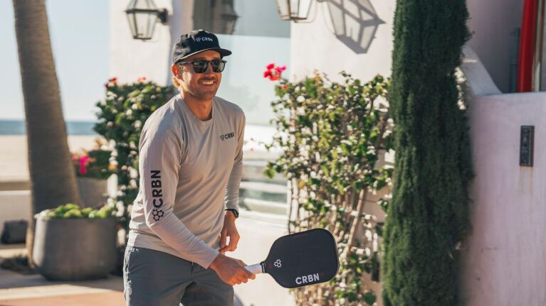 Smiling man wearing CRBN gear with paddle bat