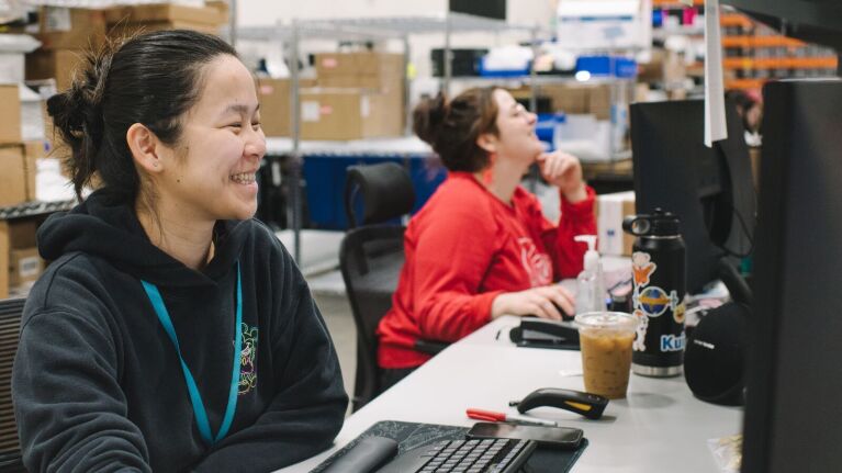 Smiling woman working at desk in warehouse