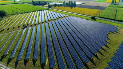 An image of a field of solar panels with lush, green fields in the background