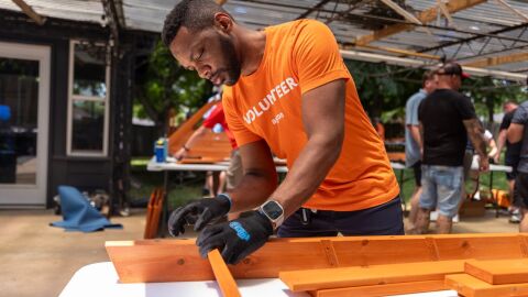 Amazon employee wearing orange 'Volunteer' t-shirt constructing with lumber