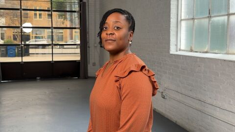 An image of a woman wearing an orange shirt standing inside of a building.