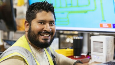 Amazon employee with his back turned to a computer and smiling. 