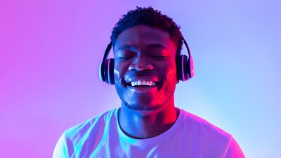 A man with headphones on, eyes closed, and smiling.