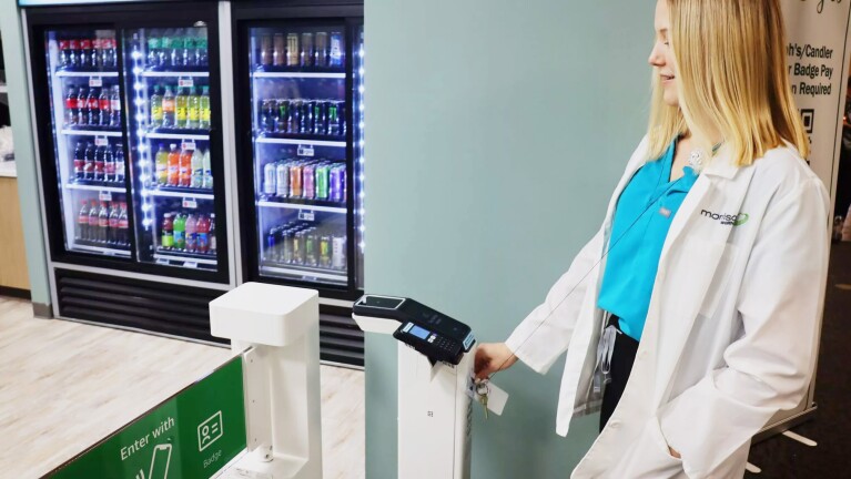 A photo of a hospital employee scanning their badge using Just Walk Out technology to enter a hospital retail store.