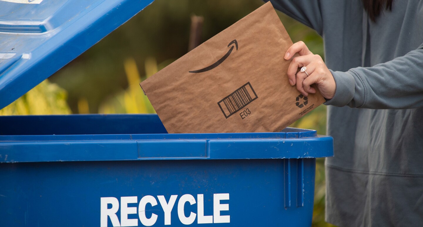 An image of a person putting an Amazon package in the recycle bin.