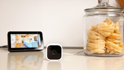 An Amazon Blink indoor camera and monitor sitting on a kitchen counter. 