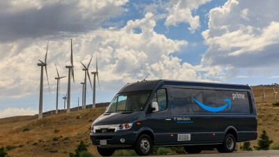An Amazon truck drives past wind turbines