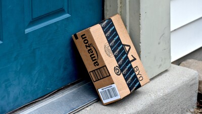 An Amazon package leans against the front door of a house. 