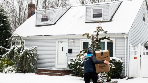 An Amazon driver delivers packages to a home during the winter.