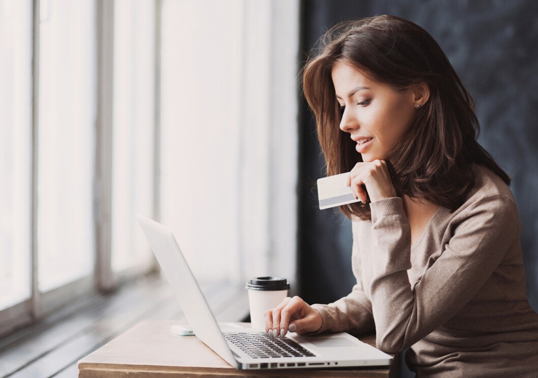 Woman working on laptop, holding a card