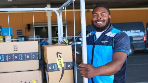 An image of an Amazon employee with a cart of packages.