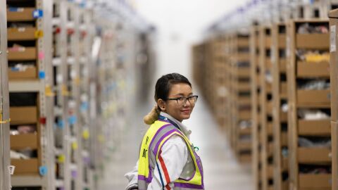 A photo of an employee standing in an aisle at an Amazon fulfillment center.