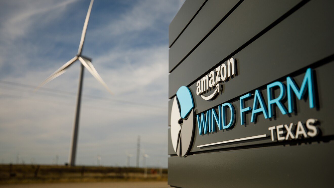 View of the sign entering the Amazon Wind Farm in Texas with a wind turbine in the background.