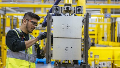 Amazon employee working with robotic machinery in a fulfillment center. 